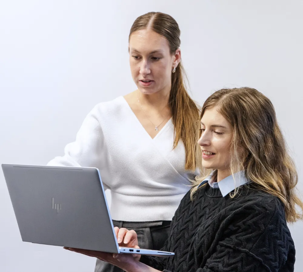 Two female marketing professionals Two female marketing professionals discussing something in front of a laptop