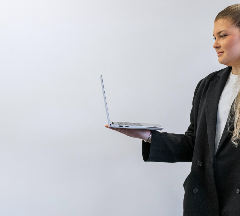 Screenshot 2025-08-29 at 3.12.14 PM Female marketing professional holding laptop on one hand with arm at 90 degree angle