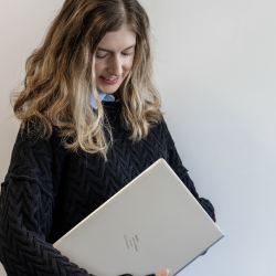 Screenshot 2025-08-29 at 8.59.54 AM Female marketing professional holding laptop and looking down on it
